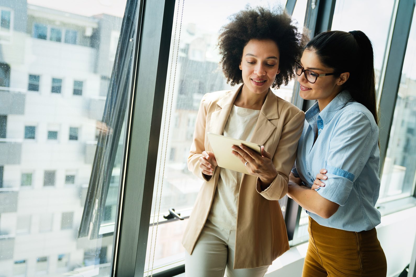 two-business-women-discussing-work-near-a-window